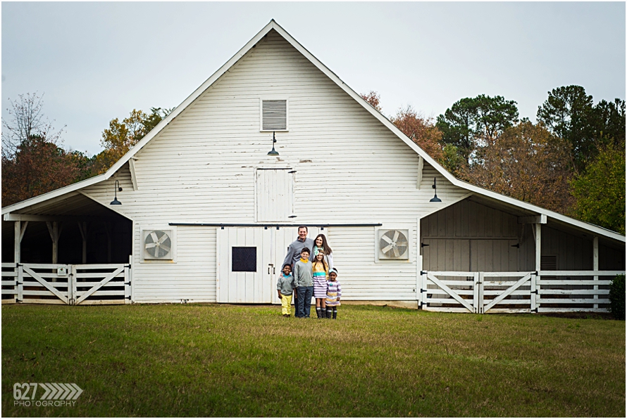 large family in front of white barn