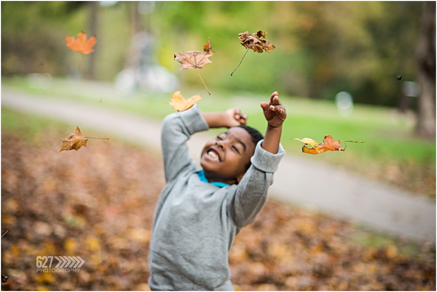 little boy throwing leaves in the air
