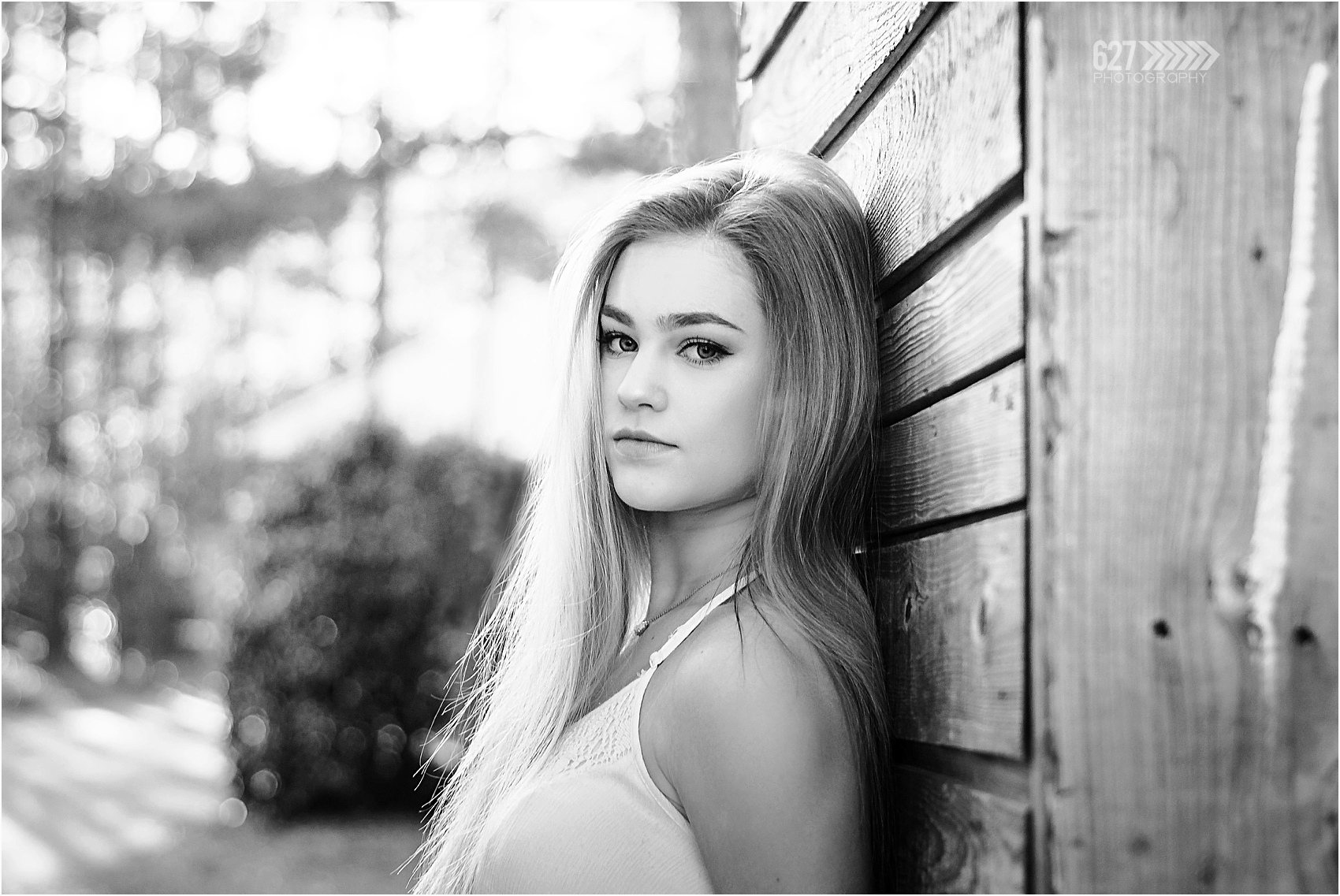 black and white photo senior girl leaning on wood wall