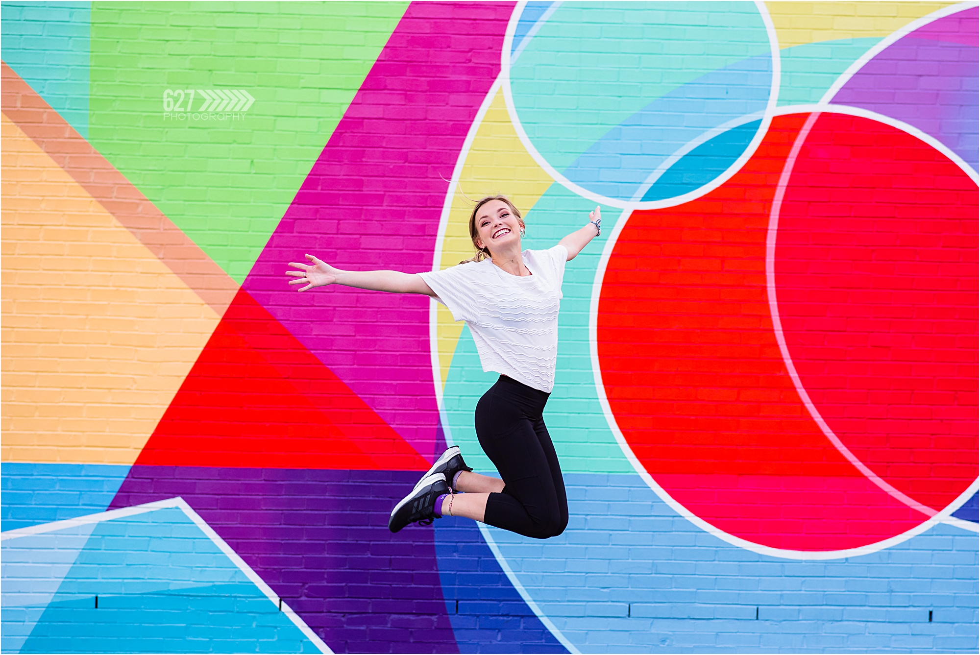 senior girl jumping shot colorful mural