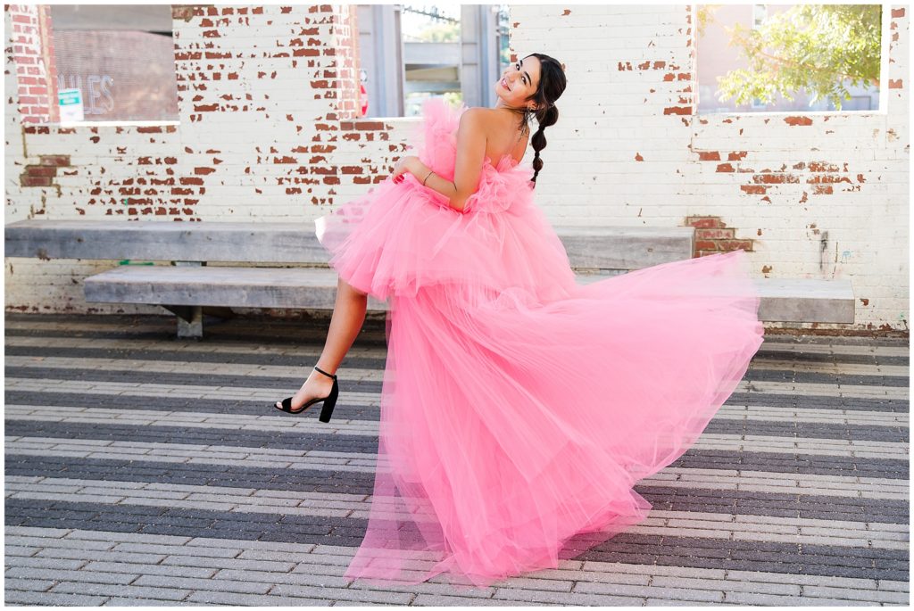 senior girl wearing big pink tulle dress downtown