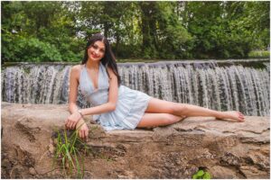 Senior girl standing by a creek with small waterfall