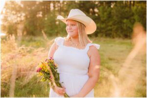 High school senior wearing a cowboy hat in the golden sunset during a country senior session.