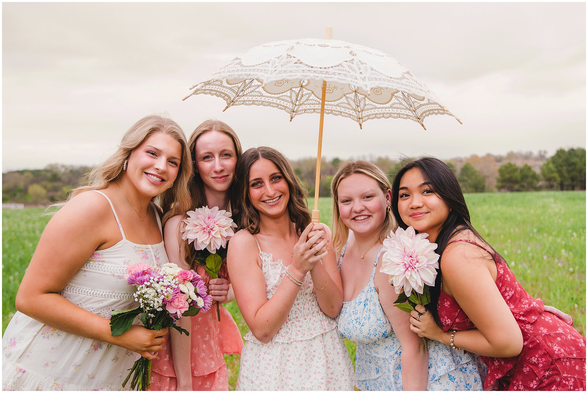 High school seniors gathered around a Pinterest-inspired picnic setup during a spring photography session.