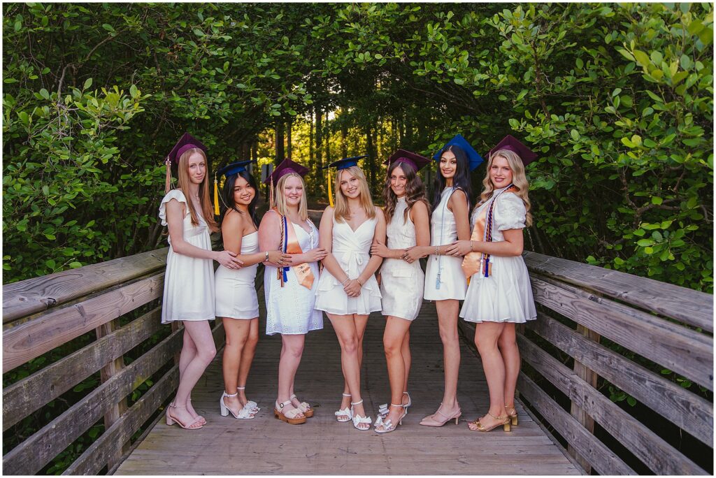 Seven Raleigh seniors wearing white dresses and graduation caps