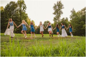 Senior girls holding hands walking through an open field