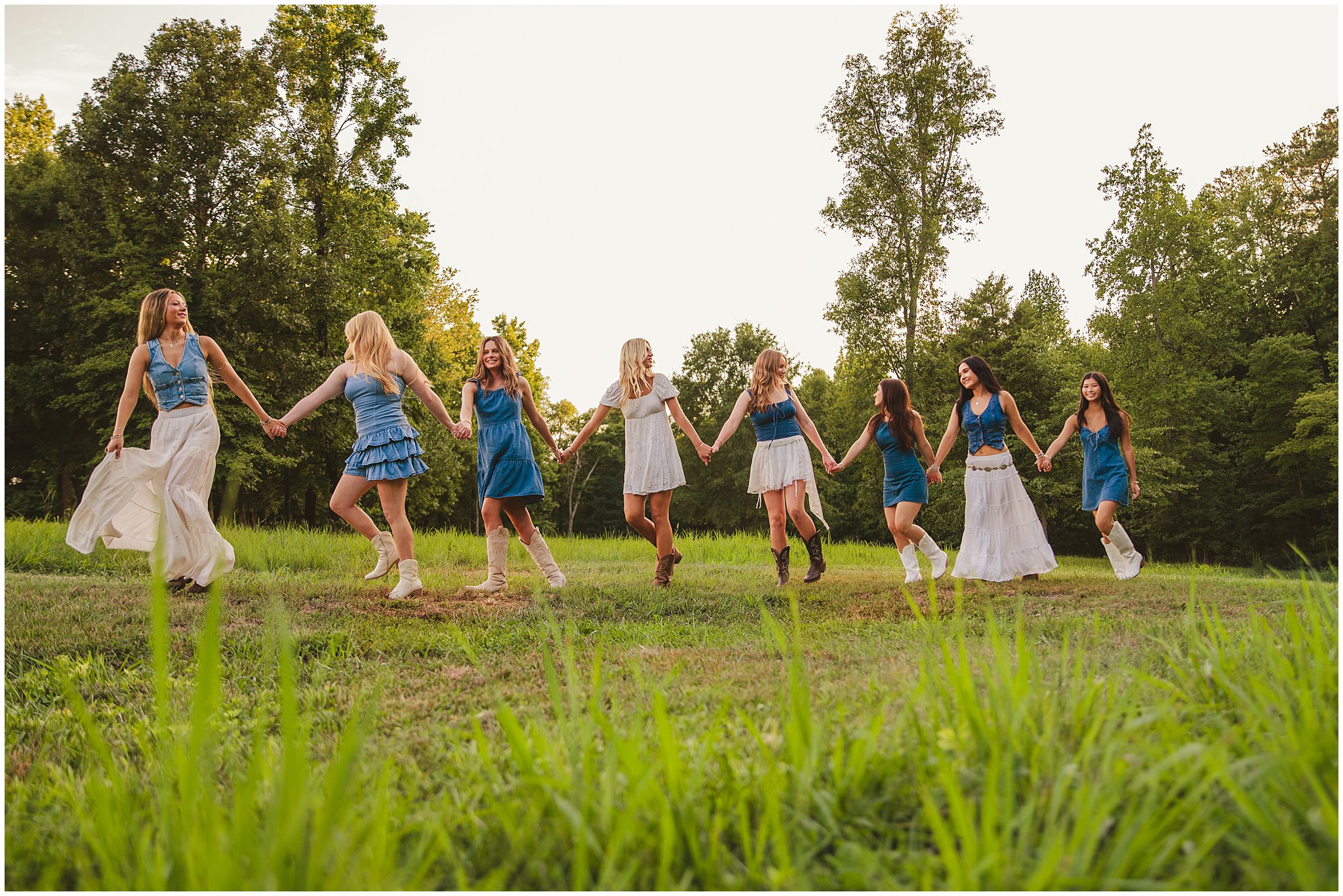 Senior girls holding hands walking through an open field